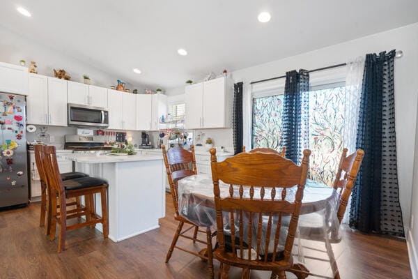 kitchen with lofted ceiling, stainless steel appliances, light countertops, a kitchen breakfast bar, and a center island