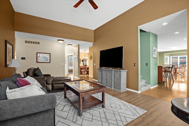 living room featuring visible vents, light wood-style flooring, a ceiling fan, recessed lighting, and baseboards