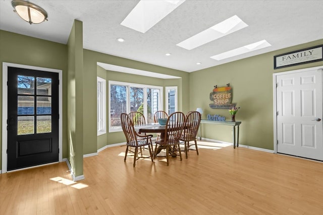 dining room featuring baseboards, a textured ceiling, and light wood finished floors