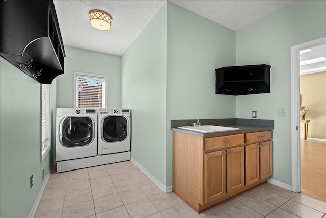 laundry room with washing machine and clothes dryer, light tile patterned flooring, a textured ceiling, and a sink