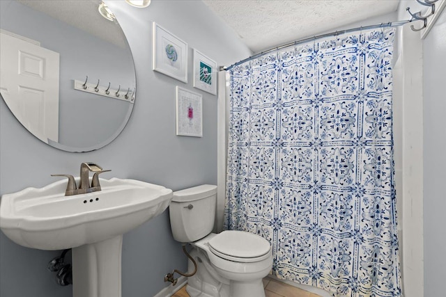 bathroom featuring toilet, a textured ceiling, a shower with shower curtain, and a sink