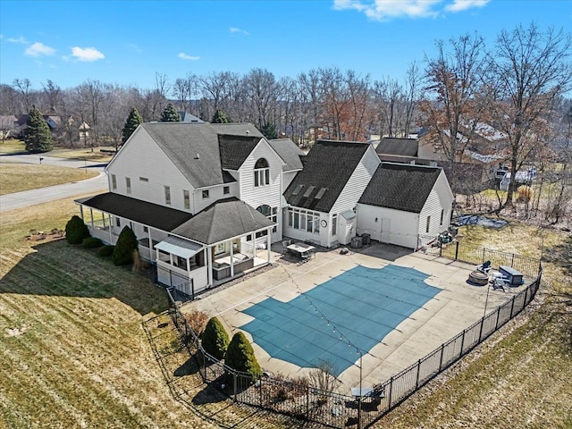 back of property with a patio, a fenced backyard, a yard, roof with shingles, and a fenced in pool