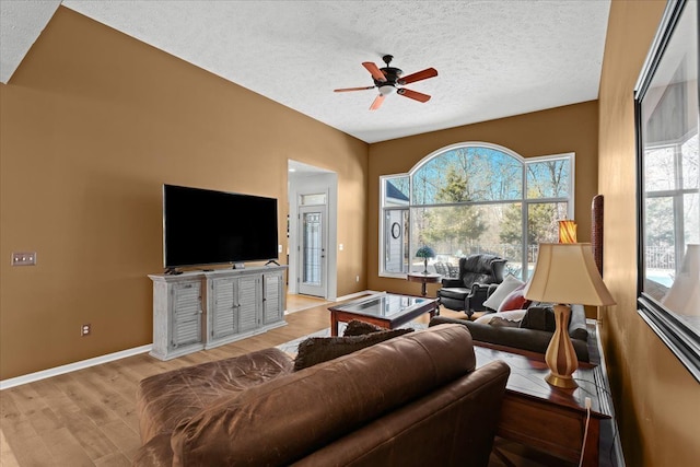 living room featuring ceiling fan, a textured ceiling, baseboards, and wood finished floors