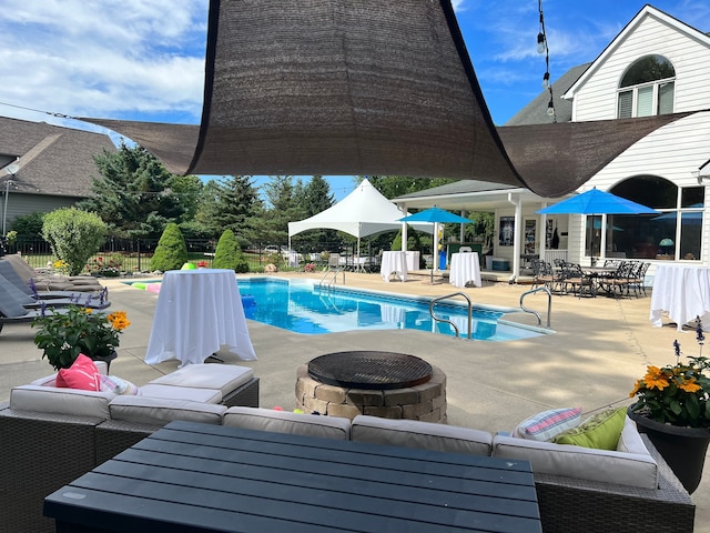 pool with an outdoor living space with a fire pit, a patio, and fence