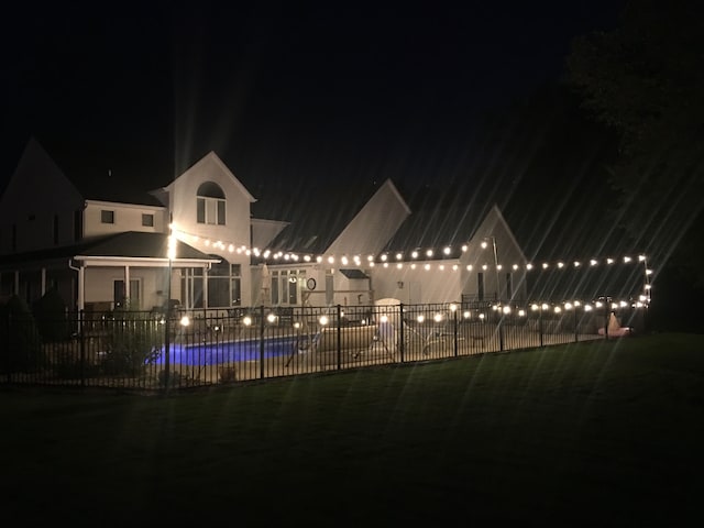 pool at night with a fenced in pool and fence