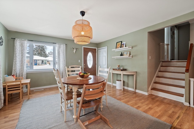 dining room featuring light wood finished floors, stairs, and baseboards