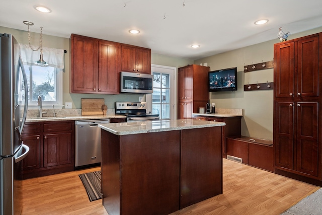 kitchen with a sink, light wood-style flooring, a wealth of natural light, and stainless steel appliances