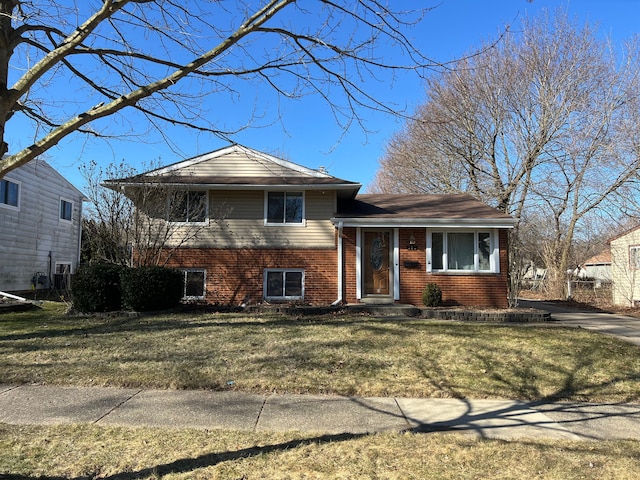 tri-level home with a front yard and brick siding