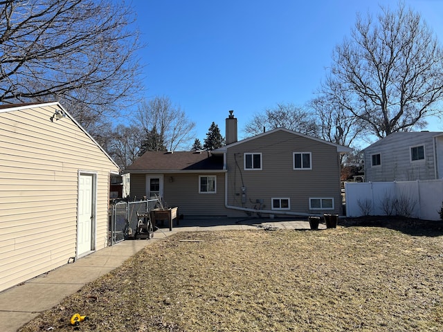 back of house featuring a chimney, a patio, and fence