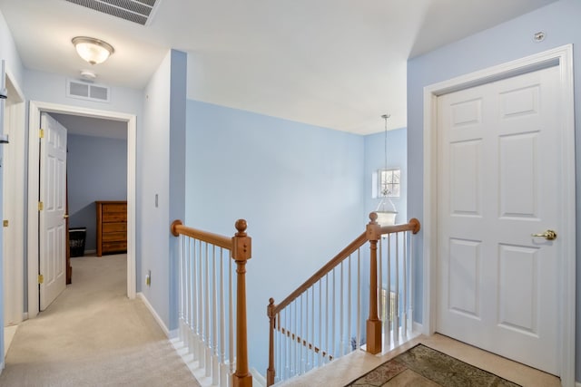 corridor featuring baseboards, visible vents, an upstairs landing, and carpet floors