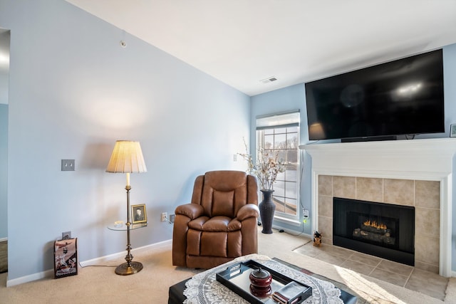 living area with visible vents, baseboards, carpet flooring, and a tiled fireplace