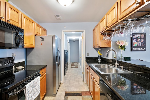 kitchen featuring visible vents, a sink, dark stone countertops, black appliances, and separate washer and dryer