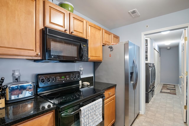 kitchen featuring dark stone counters, light floors, black appliances, and washer and clothes dryer