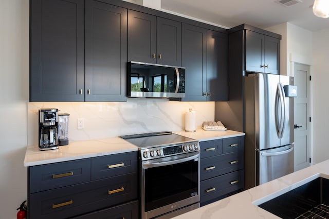 kitchen featuring visible vents, a sink, appliances with stainless steel finishes, decorative backsplash, and light stone countertops