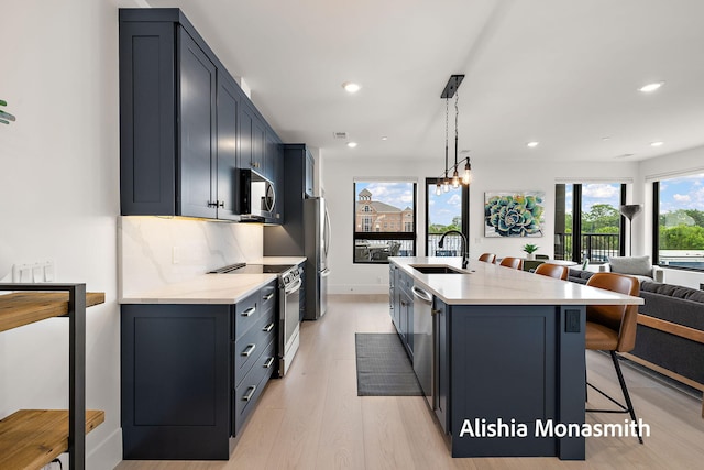 300 Washington Ave Unit 1, Grand Haven, MI 49417 - kitchen featuring appliances with stainless steel finishes, light wood-style flooring, a breakfast bar, recessed lighting, and a center island with sink