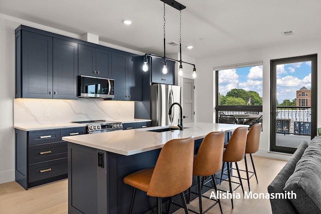 300 Washington Ave Unit 1, Grand Haven, MI 49417 - kitchen with stainless steel appliances, tasteful backsplash, a kitchen breakfast bar, an island with sink, and recessed lighting
