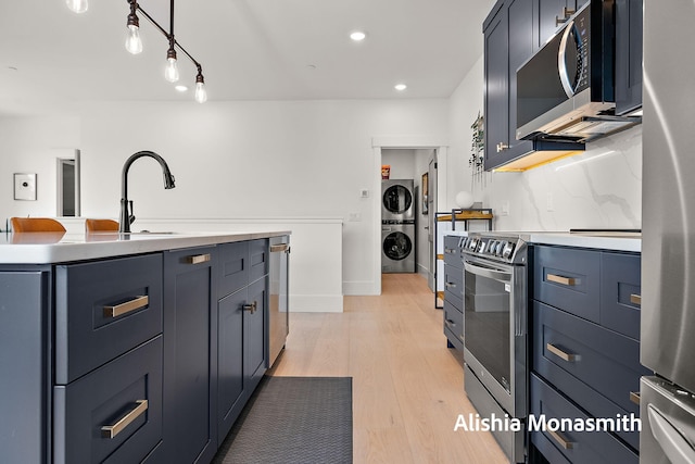 300 Washington Ave Unit 1, Grand Haven, MI 49417 - kitchen featuring estacked washer and dryer, stainless steel appliances, light wood-style flooring, light countertops, and recessed lighting