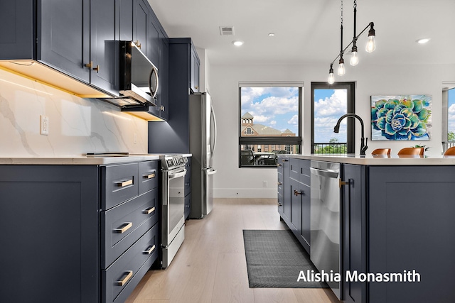 300 Washington Ave Unit 1, Grand Haven, MI 49417 - kitchen featuring appliances with stainless steel finishes, pendant lighting, light wood-style flooring, recessed lighting, and an island with sink