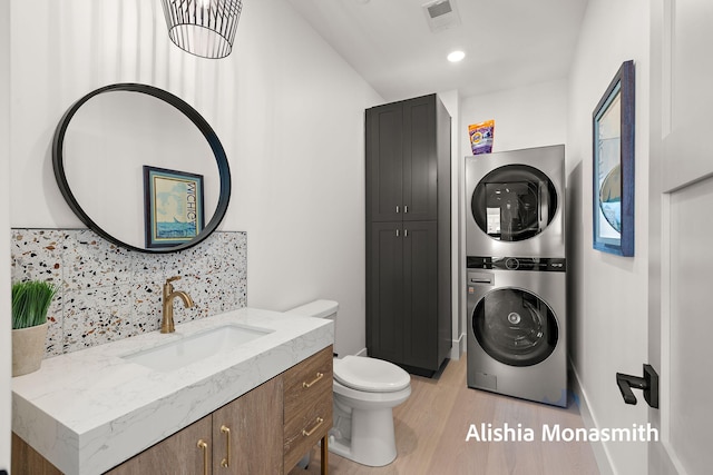 300 Washington Ave Unit 1, Grand Haven, MI 49417 - bathroom with stacked washer and clothes dryer, tasteful backsplash, vanity, wood finished floors, and recessed lighting