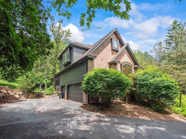 view of property exterior featuring a garage, brick siding, and aphalt driveway