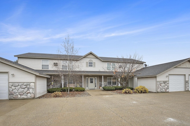 view of front of home featuring a garage, stone siding, and an outdoor structure