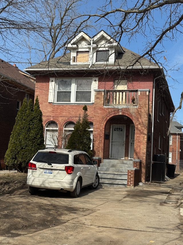 view of front of property featuring a balcony and brick siding