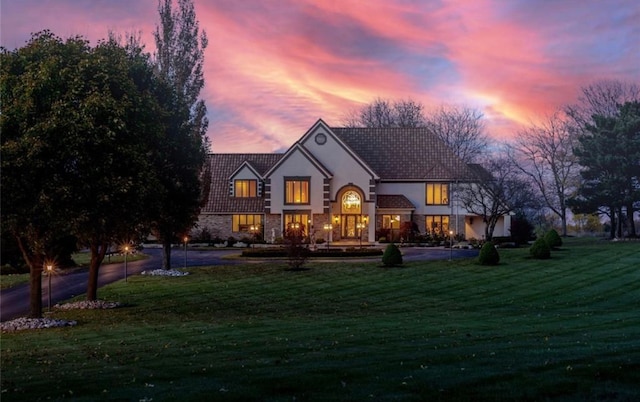 view of front facade with a yard, stone siding, and stucco siding