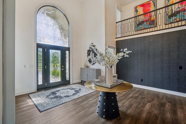 foyer with a high ceiling, baseboards, and wood finished floors