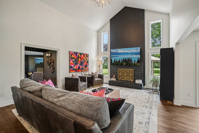 living area with a fireplace, high vaulted ceiling, baseboards, and wood finished floors