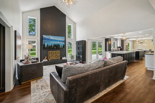 living area with dark wood finished floors, high vaulted ceiling, a fireplace, and a chandelier