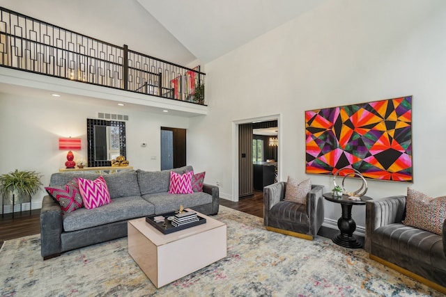 living room with visible vents, baseboards, high vaulted ceiling, and wood finished floors