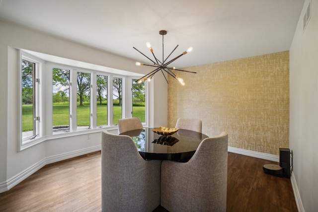 dining room with a chandelier, visible vents, baseboards, and wood finished floors