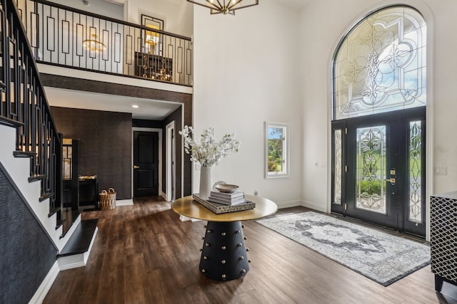 entrance foyer featuring baseboards, wood finished floors, a towering ceiling, and stairs