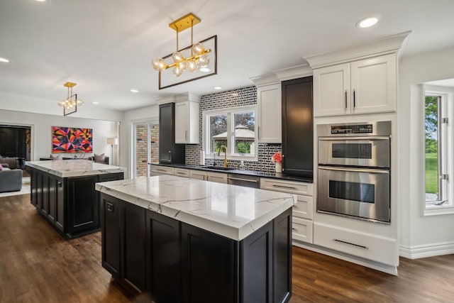 kitchen featuring a center island, appliances with stainless steel finishes, an inviting chandelier, dark wood-style floors, and a sink