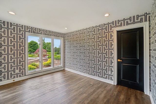 unfurnished room featuring wallpapered walls, dark wood finished floors, and baseboards