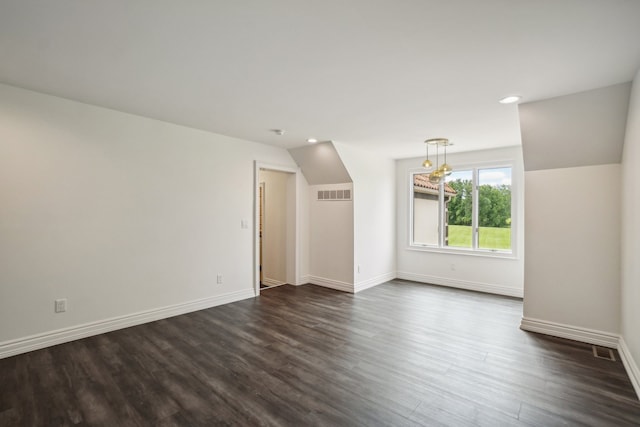 unfurnished room featuring visible vents, baseboards, dark wood-style flooring, and vaulted ceiling