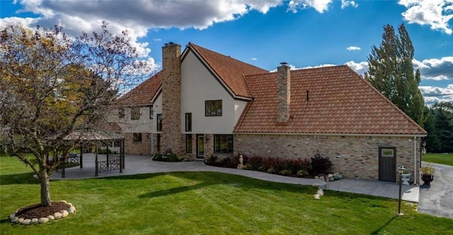 exterior space with a patio, a yard, a chimney, a gazebo, and a tiled roof