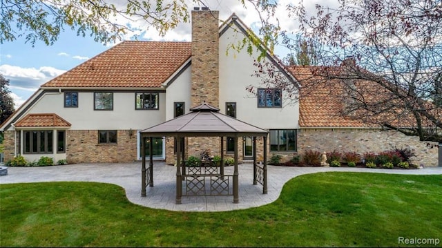 rear view of property featuring a gazebo, a lawn, a patio, and stucco siding