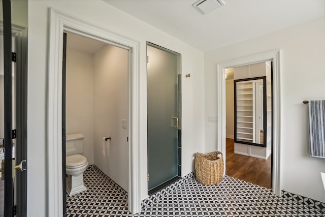 bathroom with toilet, visible vents, and a stall shower