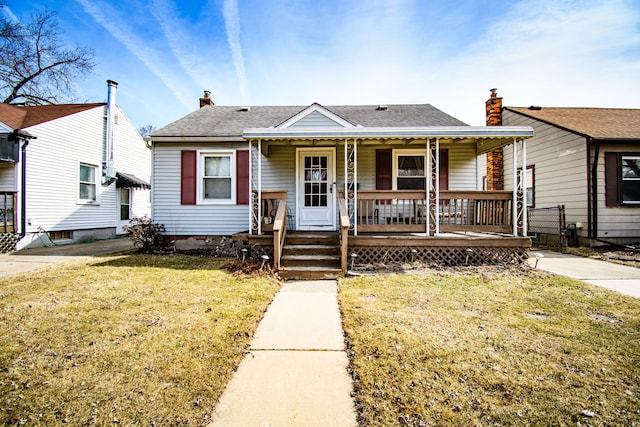 bungalow with a porch, a front yard, roof with shingles, and a chimney