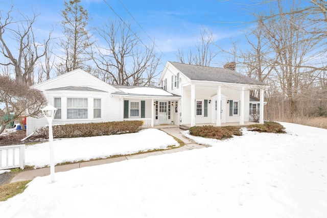 neoclassical home featuring a chimney and fence