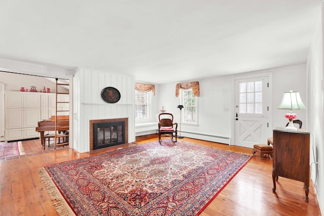 living area with a fireplace with flush hearth, wood finished floors, and baseboard heating