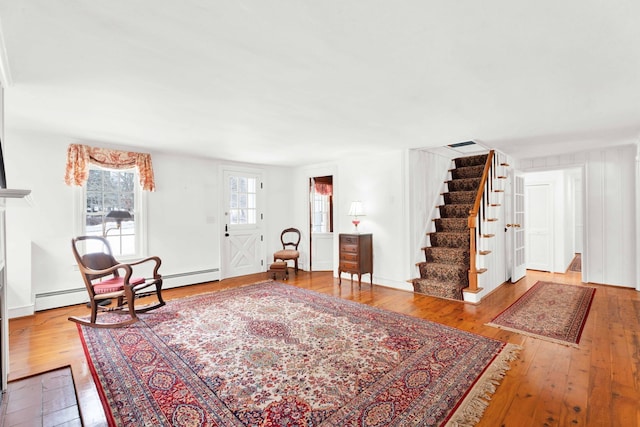 interior space with stairs, hardwood / wood-style flooring, visible vents, and a baseboard radiator