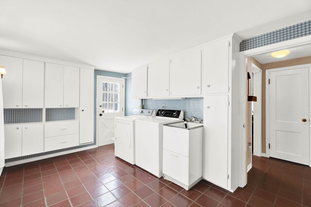 clothes washing area featuring washer and clothes dryer, cabinet space, and dark tile patterned flooring