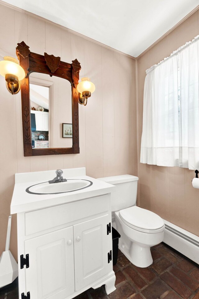 half bathroom with baseboard heating, toilet, and vanity