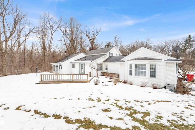 snow covered house with a chimney and a wooden deck