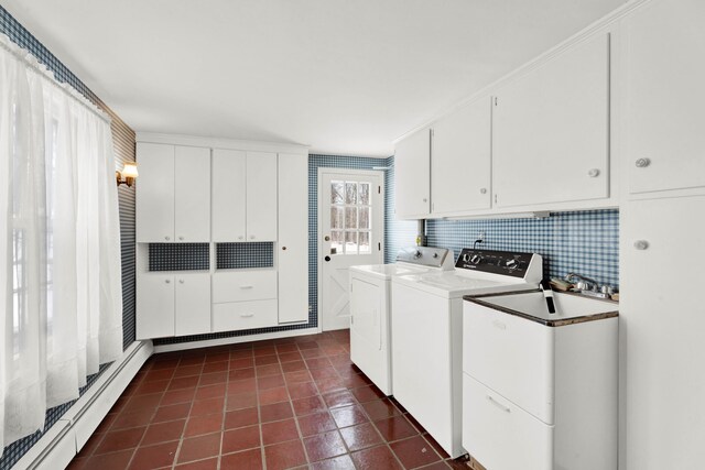 laundry room featuring washing machine and dryer, dark tile patterned floors, cabinet space, and baseboard heating