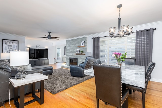 dining room featuring light wood finished floors, ceiling fan with notable chandelier, a wealth of natural light, and ornamental molding