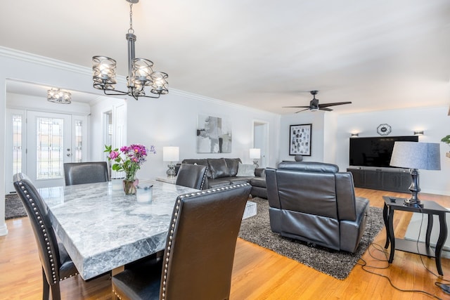 dining area featuring ceiling fan with notable chandelier, light wood-style flooring, and ornamental molding