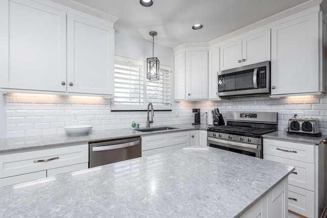 kitchen with a sink, stainless steel appliances, decorative backsplash, and white cabinetry